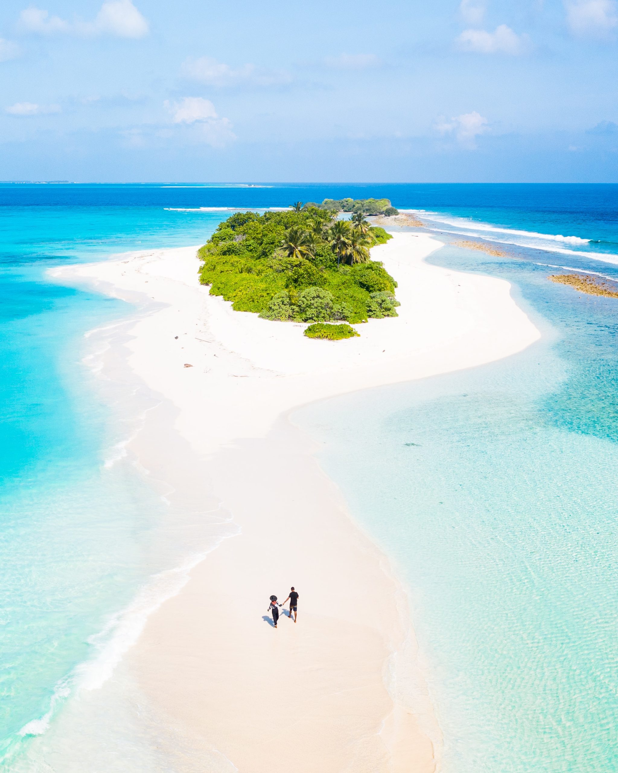 aerial view of couple walking on white sand beach in the Maldives